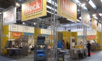 Systemstand mit kassettierter und hinterleuchteter Wand und aufgeständerten Deckenbannern.
