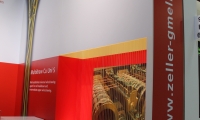 Mischbaustand bestehend aus vorgehängten Wänden mit vollflächigen Digitaldrucken und abgehängtem Bannerkubus.
